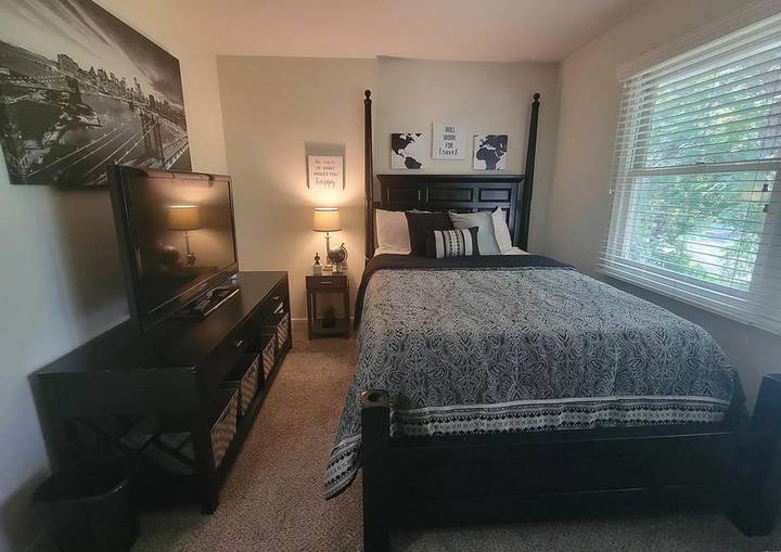 Original listing photo of a bedroom with a dark four-poster bed and a TV stand