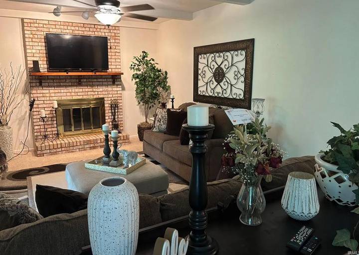 Original listing photo of the family room with a brick fireplace, wall-mounted TV and sliding glass door