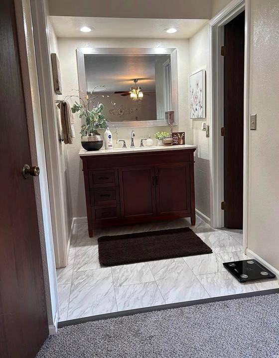 Original listing photo of the primary bathroom with a bathroom scale on the floor